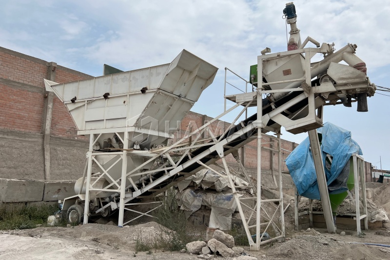 Truck mixers being loaded under a dry batching plant on a road project